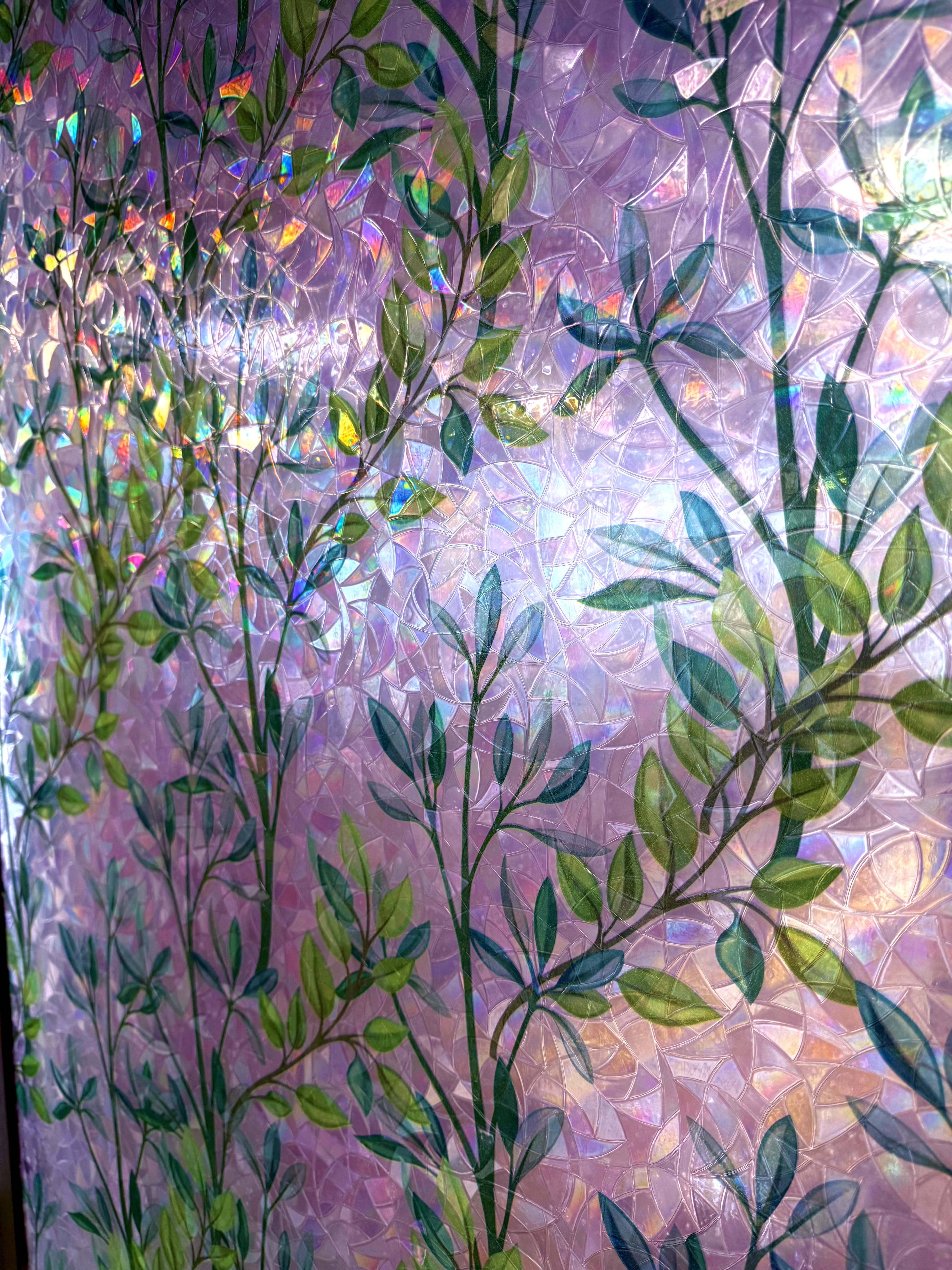 An iridescent leaf-patterned wall panel catching rainbow light