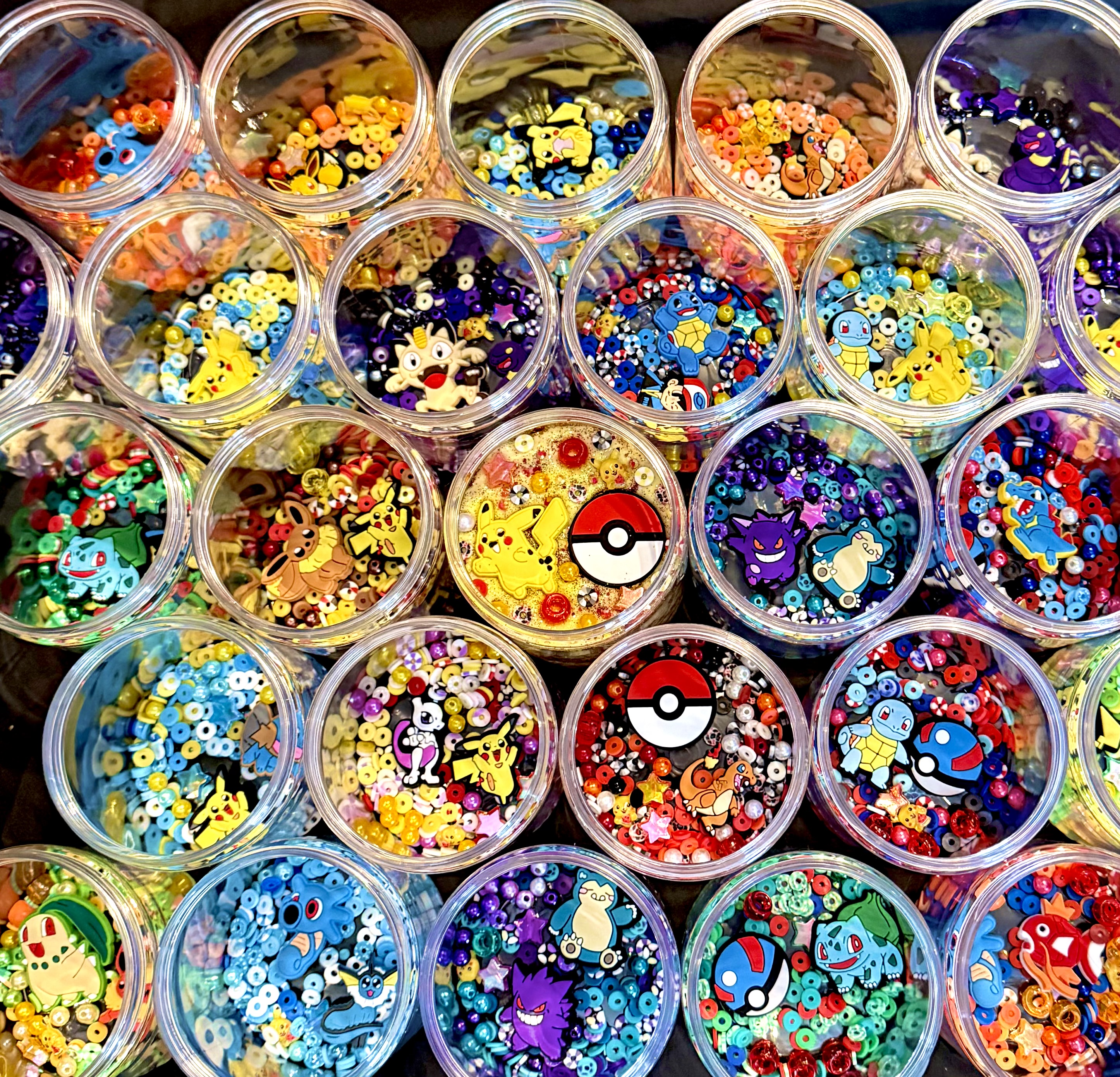 Pots of colourful craft beads and charms photographed from above